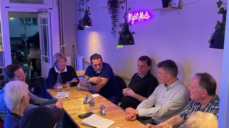 Eine Gruppe Personen sitzt an einem Tisch in einem Restaurant und unterhält sich.