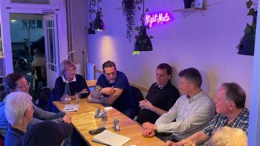 Eine Gruppe Personen sitzt an einem Tisch in einem Restaurant und unterhält sich.